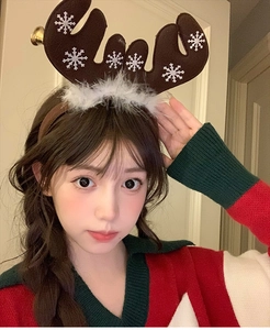 Detailed view of Christmas reindeer headband with white snowflakes and festive golden bell