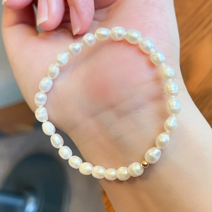 Detail of baroque pearl bracelet with gold bead on wrist showing natural luster