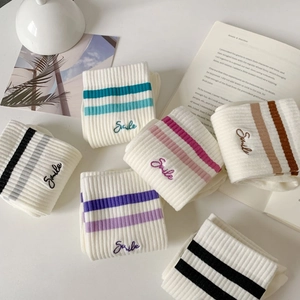 Close-up of ribbed sports socks featuring colorful stripes and Smile embroidery detail