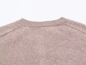 Detailed view of the ribbed knit crewneck collar and soft oatmeal fabric texture