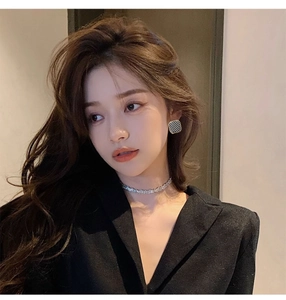 Close-up of model wearing square checkerboard stud earrings and a silver choker necklace