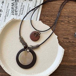 Detail of bohemian butterfly necklace featuring layered wood and bronze pendants on wax cord