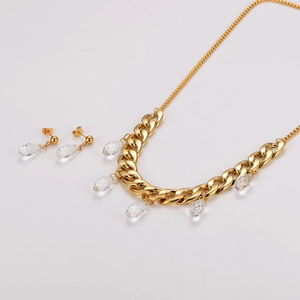 Detail of gold Cuban chain necklace and earrings with clear crystal teardrop pendants
