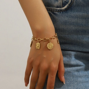 Gold stainless steel bracelet featuring starburst and sun pendants on a model's wrist