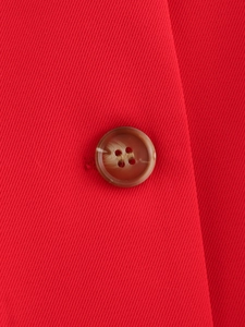 Close-up of red twill fabric detail and brown marbled button on summer vest