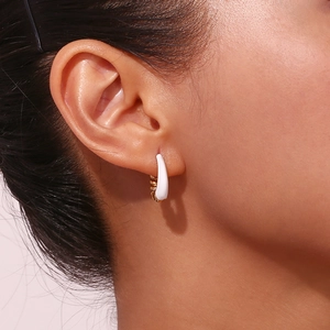 Detailed view of twisted pear-shaped ear cuff with white enamel and gold finish on ear