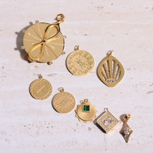 Set of 9 gold-plated zodiac and evil eye pendants with red gemstones and engravings