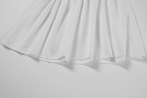 Vue détaillée de l'ourlet en mousseline blanche plissée avec couture professionnelle
