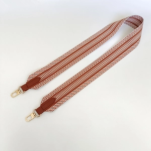 Detail of brown and white woven canvas strap with leather ends and gold metal clasps