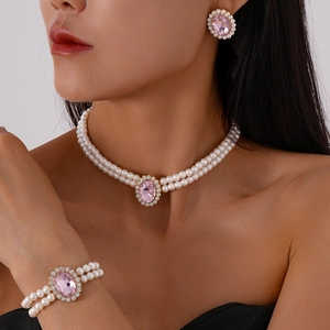 Close-up of a luxury three-piece pearl jewelry set with pink oval gemstones on a model