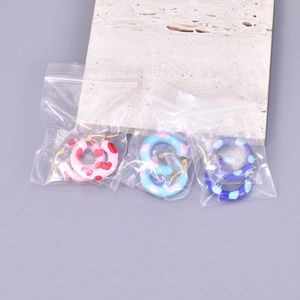 Detail view of 18k gold plated enamel hoop earrings in three vibrant dotted color styles