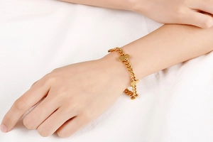 Close-up of a gold stainless steel pineapple pendant bracelet on a woman's wrist