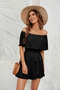 Detail of the black off-shoulder pleated romper featuring a matching waist belt and texture