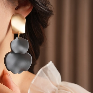 Close-up of a model wearing gold and grey irregular pleated petal earrings with silver pins