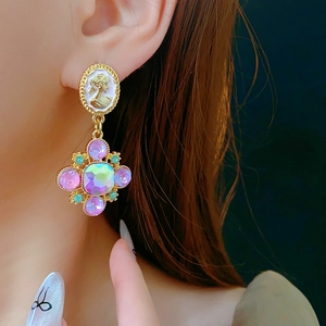 Detail of vintage gold earrings featuring white relief portrait and colorful gemstones