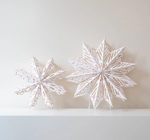 Close-up of Nordic paper snowflake star ornaments with red candy cane patterns