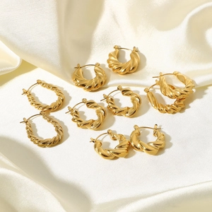 Set of gold-plated stainless steel twisted hoop earrings on elegant yellow silk fabric