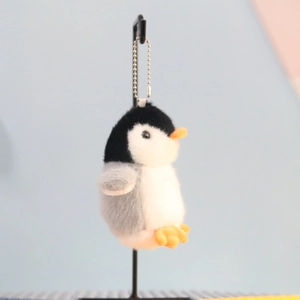 Close-up of cute penguin plush keychain with orange beak and metal bead chain detail