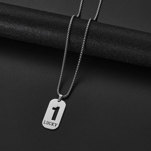 Macro shot of silver stainless steel pendant engraved with LUCKY and number 1 on dark surface