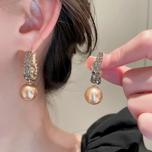 Détail de boucles d'oreilles perles dorées avec double cercle en strass sur le mannequin