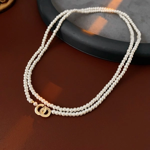 Detailed close-up of double-layer faux pearl necklace with gold interlocking rings
