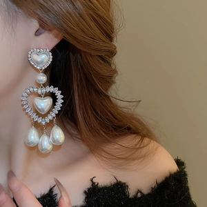 Dettaglio ravvicinato di orecchini di perle a forma di cuore con strass su una modella