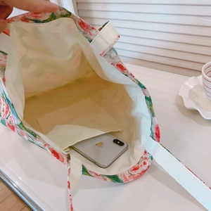 Detail showing inner open pocket of red floral canvas tote bag with smartphone for scale