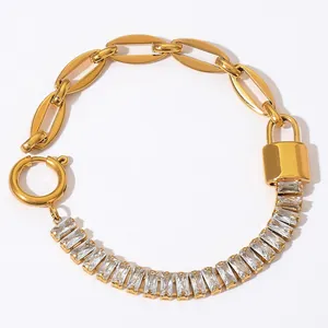 Detail of a gold link bracelet with rectangular cubic zirconia and a lock pendant charm