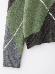 Détail d'un pull en maille à losanges montrant les poignets côtelés et la texture laine