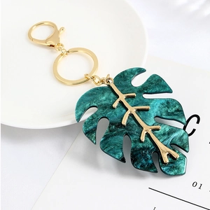 Detail of green monstera leaf keychain with gold veins and marble resin texture
