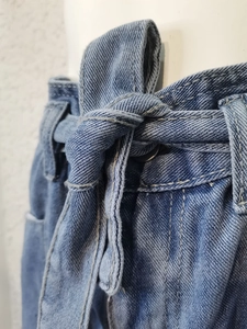Dettaglio di pantaloncini in denim azzurro con nodo in vita e cuciture rifinite