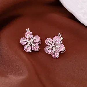 Boucles d'oreilles fleurs en zircon rose avec étoiles argentées sur tissu de soie brun