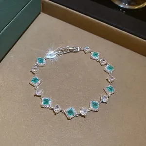 Sparkling zircon silver bracelet featuring emerald green gems on a brown velvet tray