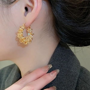 Gros plan d'une boucle d'oreille torsadée en or avec zircons portée par un mannequin