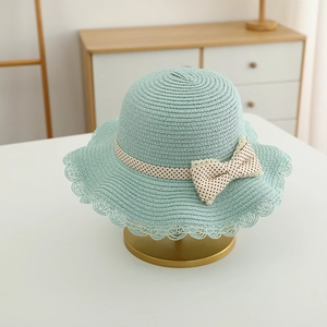 Detail of light green straw sun hat with polka dot bow and hollow lace brim design