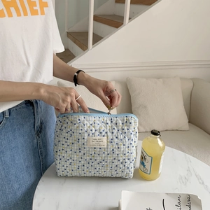 Close-up of light blue quilted makeup bag with polka dots and zipper closure