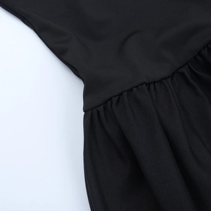 Dettaglio del tessuto in maglia nera con trama increspata e cuciture sottili dell'abito