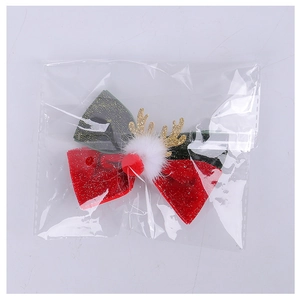 Detail of Christmas reindeer antler hair clip with red and green glitter bow in packaging