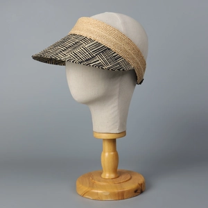 Close-up of woven raffia sun visor featuring black and white patterned brim on model