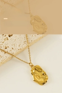 Detailed macro view of gold irregular molten pendant necklace with hammered texture