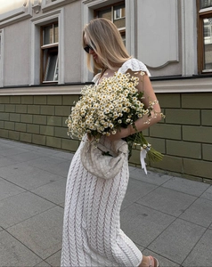 Détail d'une robe en dentelle blanche avec sac tissé pour un style bohème de vacances