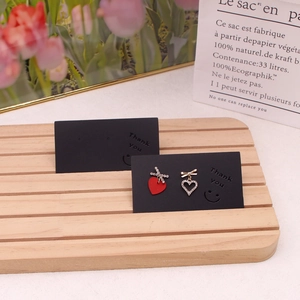 Asymmetric heart stud earrings with red and white crystal accents on a display card