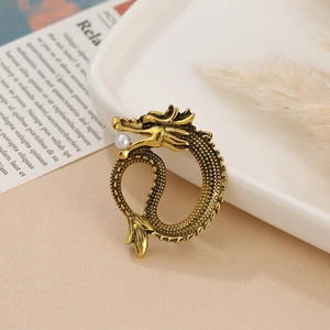 Detailed close-up of a vintage golden dragon brooch with an elegant pearl in its mouth