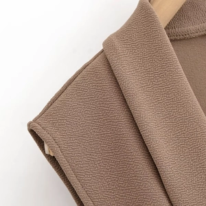 Detail shot of the tan textured crepe fabric showing the lapel and shoulder construction