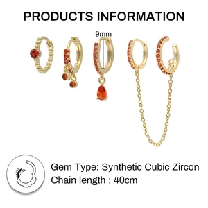 Detail of four-piece gold earring set with red cubic zirconia and chain cuff link