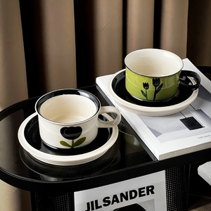 Close-up of vintage floral ceramic coffee cups in white and green on a glass table
