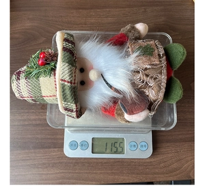Detailed view of handmade Christmas doll weight showing 115.5g on a digital scale