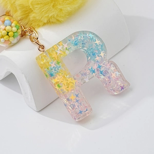Resin letter R keychain with holographic stars, gold chain and yellow pompom charm