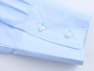 Detail eines hellblauen Popeline-Hemdärmels mit eleganten weißen Perlenknopfverschlüssen