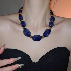Detail of blue acrylic irregular beaded necklace with gold metal spacers on model
